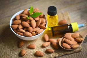 Almond oil and Almonds nuts on bowl, Delicious sweet almonds oil in glass bottle, roasted almond nut for healthy food and snack organic vegetable oils for cooking or spa concept photo