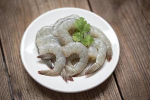 raw shrimp on white plate and wooden background for cooking close up fresh shrimps or prawns Seafood shelfish photo