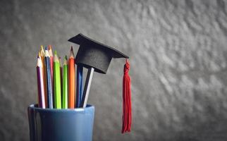 Education and back to school concept with graduation cap on pencils colour in a pencil case on dark background photo