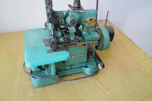 A green overlock machine for sewing clothes is placed on the table photo