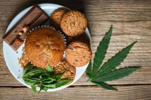 Cannabis food cookies with cake chocolate cannabis leaf marijuana herb on wooden and dark background, delicious sweet dessert cookie with hemp leaf plant THC CBD herbs food snack and medical photo