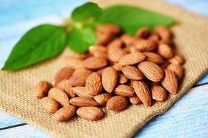 Almonds nuts with leaf , Close up almonds on sack background - Roasted almond for snack photo