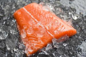 filete de salmón crudo fresco sobre hielo y fondo de piedra oscura foto