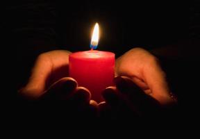 Female hands holding a burning candle in the dark photo