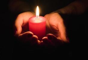 Female hands holding a burning candle in the dark photo