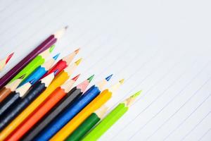 conjunto de lápices de colores en el cuaderno de papel blanco regreso a la escuela y concepto de educación crayones coloridos foto