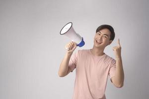 Young smiling man holding megaphone over white background studio. photo