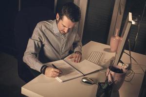 Businessman going through paperwork while working late in the evening. photo