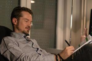 Smiling businessman writing reports while working late in the office. photo