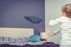 Playful boy throwing pillows in bedroom. photo