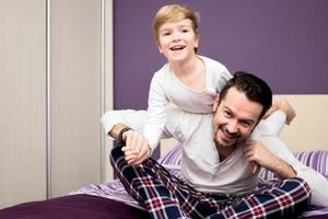 Happy father and son having fun while playing on the bed. photo