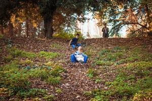 Playful kids sliding down the hill in the forest. photo