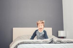 Joyful kid having fun in the morning in bedroom. photo
