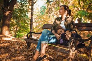 madre e hija relajándose en un banco en el parque de otoño. foto