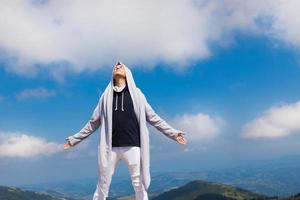 Carefree man standing on top of the mountain with arms outstretched. photo