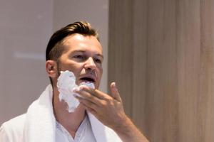 hombre aplicando espuma de afeitar en la cara por la mañana. foto