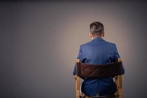 Rear view of a man sitting against the wall. photo