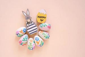Happy Easter concept with wooden bunny and colorful easter eggs on yellow background. Top view with copy space photo
