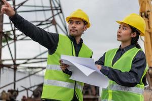 Engineers man and woman working on building site. Construction manager and architect woman meeting and discussion about project in construction site. photo