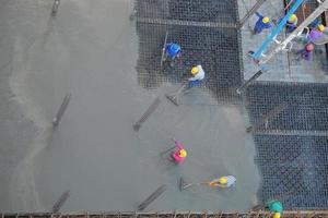 Construction site with workers wearing yellow helmets plastering photo