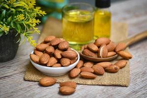 aceite de almendras y nueces de almendras en madera, delicioso aceite de almendras dulces en vidrio, nuez de almendra tostada para alimentos saludables y aceites vegetales orgánicos para refrigerios para cocinar o concepto de spa foto