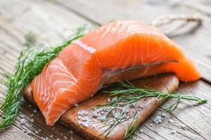 Raw salmon filet with herbs and spices on wooden background photo