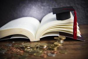 beca para el concepto de educación con moneda de dinero en madera con fondo oscuro y gorra de graduación en un libro abierto foto