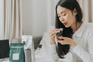 Happy woman smiling and making coffee at home. Asian woman enjoying and smelling of hot coffee in the morning. photo