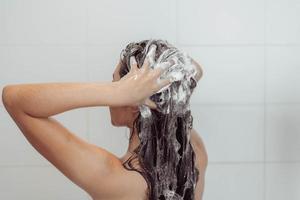 Young woman washing hair in shower. Asian woman washing her black hair. photo