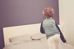 Back view of playful boy in the bedroom. photo