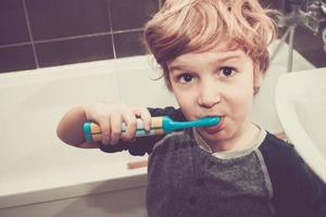 niño pequeño cepillarse los dientes en el baño. foto