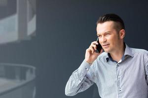 hombre de negocios adulto medio hablando por teléfono contra la pared. foto