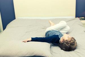 Small boy in pyjama lying down on bed. photo