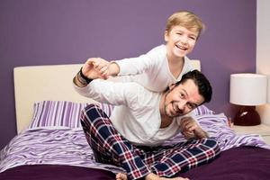 Playful father and son having fun before bedtime photo