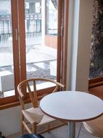 vista de una mesa vacía con una silla dentro de un café de estilo japonés mínimo cerca de la ventana foto