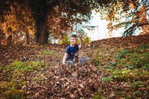 Happy boy having fun among autumn leaves. photo