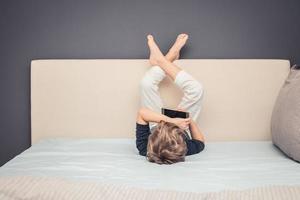 Small boy watching cartoons online while lying on the bed. photo