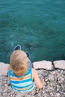 Boy relaxing on pier by the sea. photo