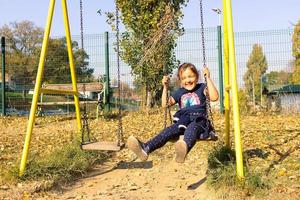 Cheerful little girl swinging in the park. photo