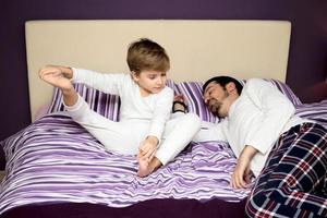 Small boy with father resting in bedroom. photo