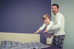 feliz padre e hijo jugando en el dormitorio. foto
