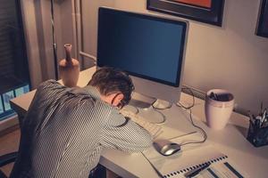 Tired businessman fell asleep while working on the computer in the office. photo