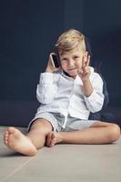 Cute kid showing victory sign while making phone call over mobile phone. photo