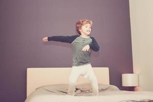 Playful boy having fun in the bedroom. photo