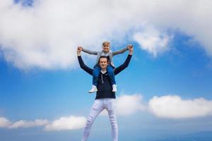 Happy father carrying son on shoulders against the sky. photo