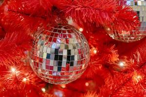Silver disco ball on a red christmas tree. Festive new year background. photo