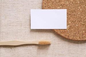 tarjeta de nombre comercial de identidad de marca plana con productos sostenibles, cepillo de dientes de bambú sobre fondo de tela, concepto mínimo de diseño foto