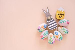 Happy Easter concept with wooden bunny and colorful easter eggs on yellow background. Top view with copy space photo