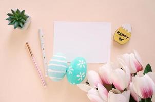 Happy Easter concept with blank card and colorful easter eggs and pink tulips. Top view with copy space photo