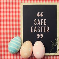 Motivational quote safe easter word on blackboard with pastel colorful easter eggs holiday background, Covid-19 and Coronavirus epidemic concept